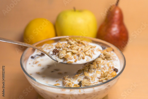 muesli in a glass bowl with milk, red pear, yellow apple, lemon