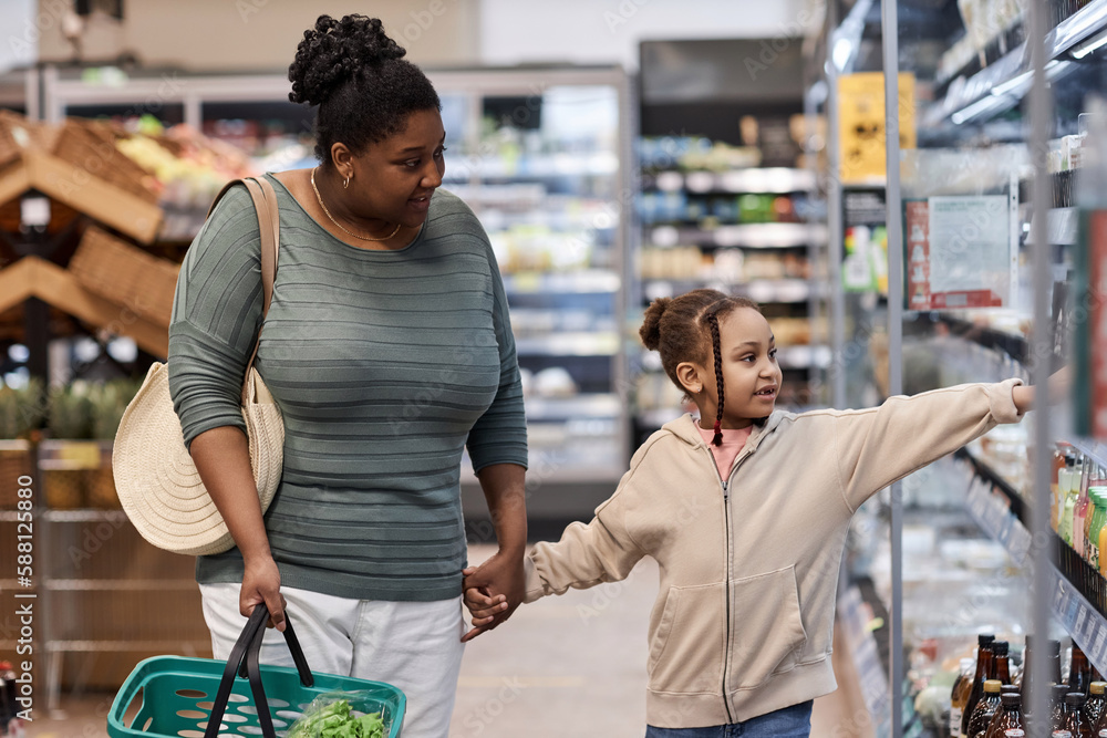 Portrait of mother and daughter in supermarket grocery shopping together
