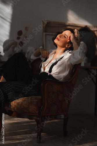 beautiful brunette woman in an armchair in the rays of the sun from the window.