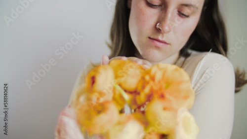 Female model posing with flowers. Close-up portrait 4K video. The young and attractive dark hair actor with dark eyes. Skincare concept video for social media. 