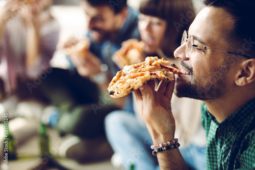 Cuadro en lienzo Close up of young man enjoying while eating pizza with his friends
