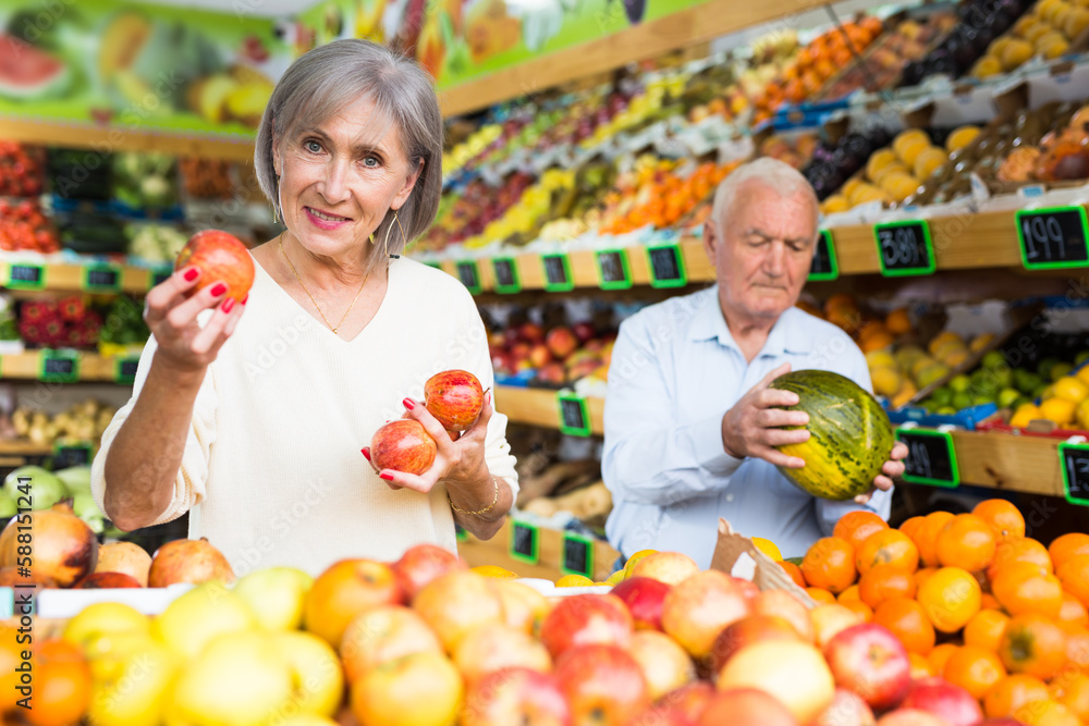 Married couple buy ripe apples and watermelon in the supermarket