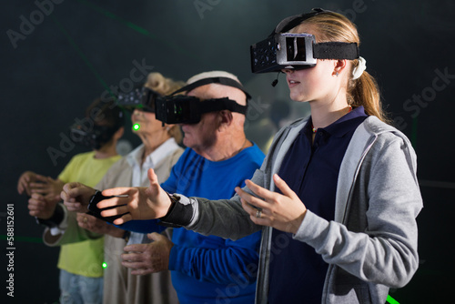 Girl in headset playing VR games with her family in dark room.