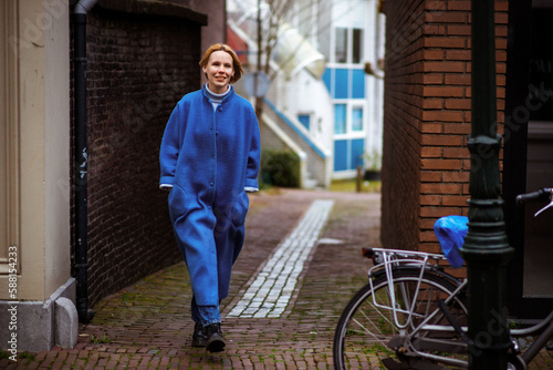 Weekend in the Netherlands, a woman in a blue coat walks along the road. Rest, travel in Europe.