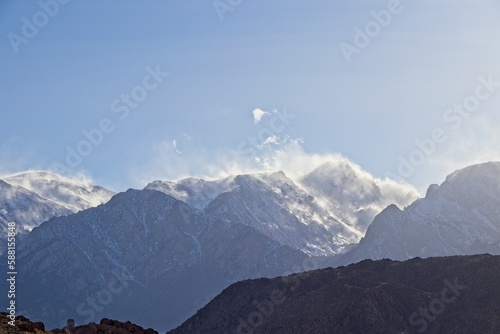 Clouds drift over the Sierra Nevada Mountains, which were dusted in snow, as seen from the Eastern Sierra