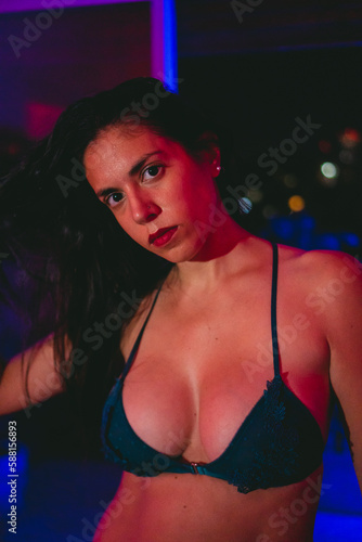 Young latin woman in bra looking at camera while playing with her hair with bokeh effect in the background. © juanpablo