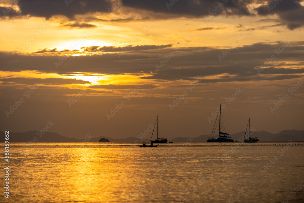 Landscape of the Ocean with tropical island mountain peak in Krabi prefecture, Thailand at summer sunset. Beautiful nature of blue sea with tourist yacht boat passing the beach on holiday vacation.