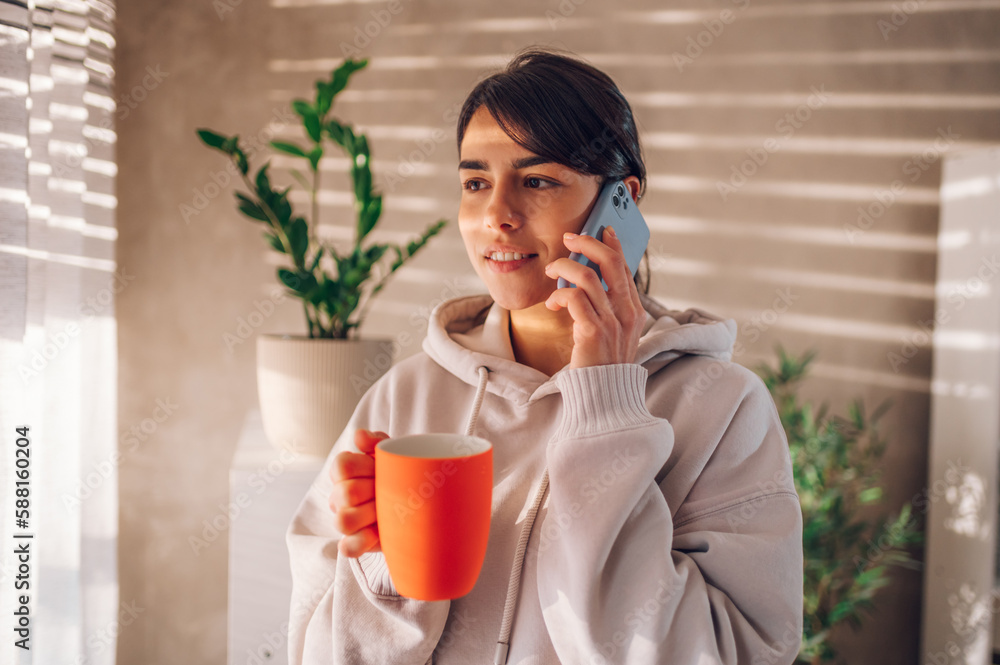 Beautiful woman talking on a smartphone and drinking coffee at home Beautiful woman talking on a smartphone and drinking coffee at home