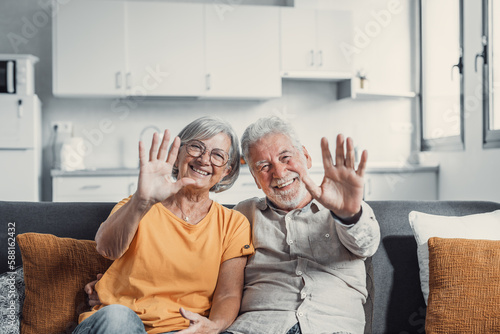 Sixty years couple, elderly parents communicates with grown up children using modern technologies makes video call, wave hands gesture of hello or goodbye sign, older generation and internet concept.