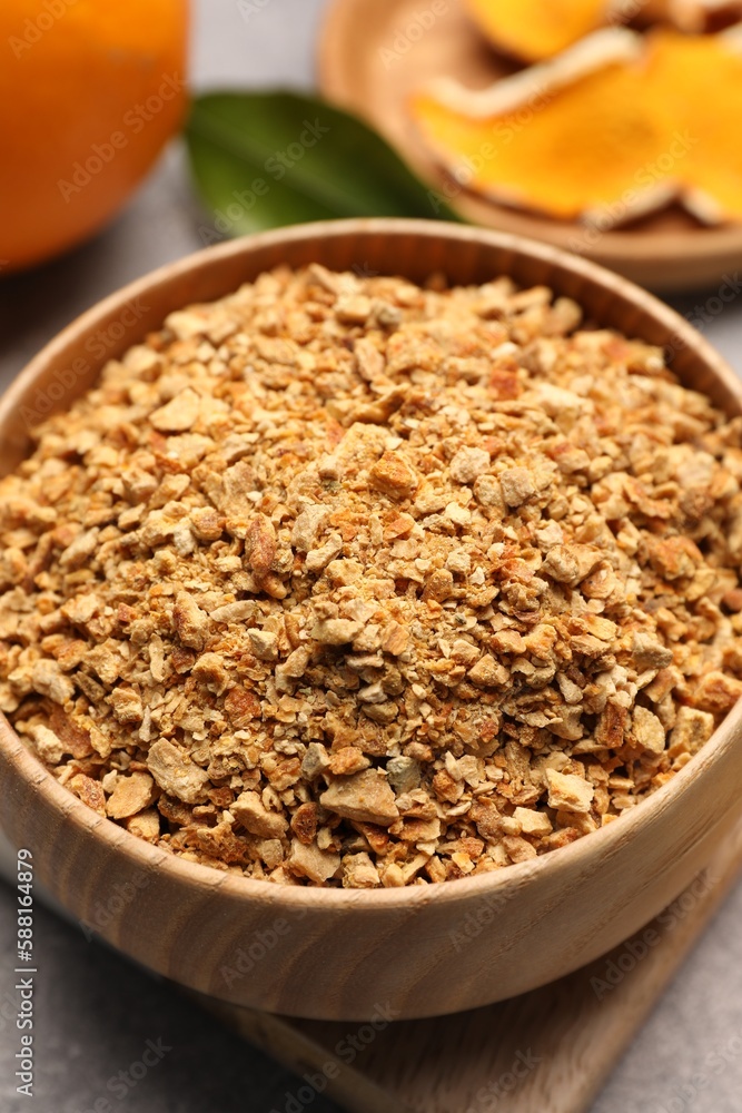 Bowl of dried orange zest seasoning and fresh fruits on light grey table, closeup Bowl of dried orange zest seasoning and fresh fruits on light grey table, closeup