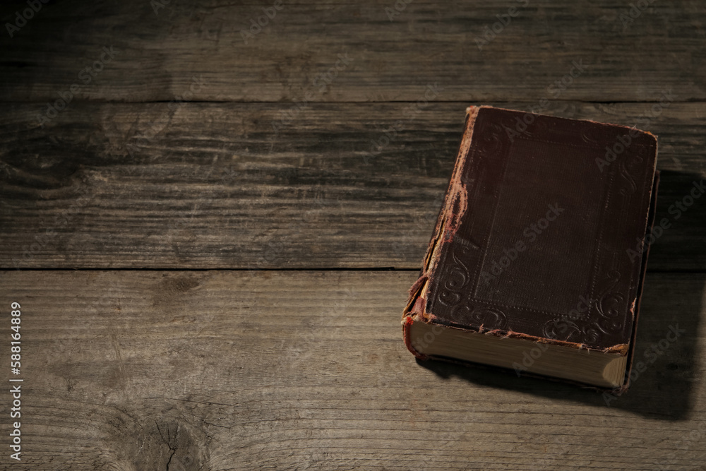 One old hardcover book on wooden table, space for text One old hardcover book on wooden table, space for text