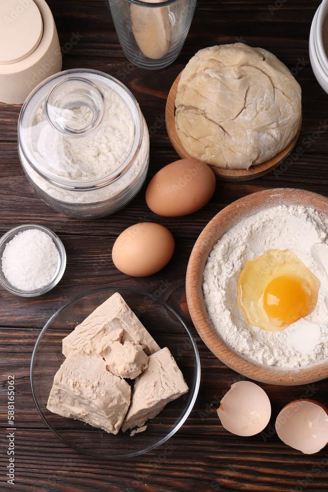 Fototapeta premium Compressed yeast, salt, flour, dough and eggs on wooden table, flat lay