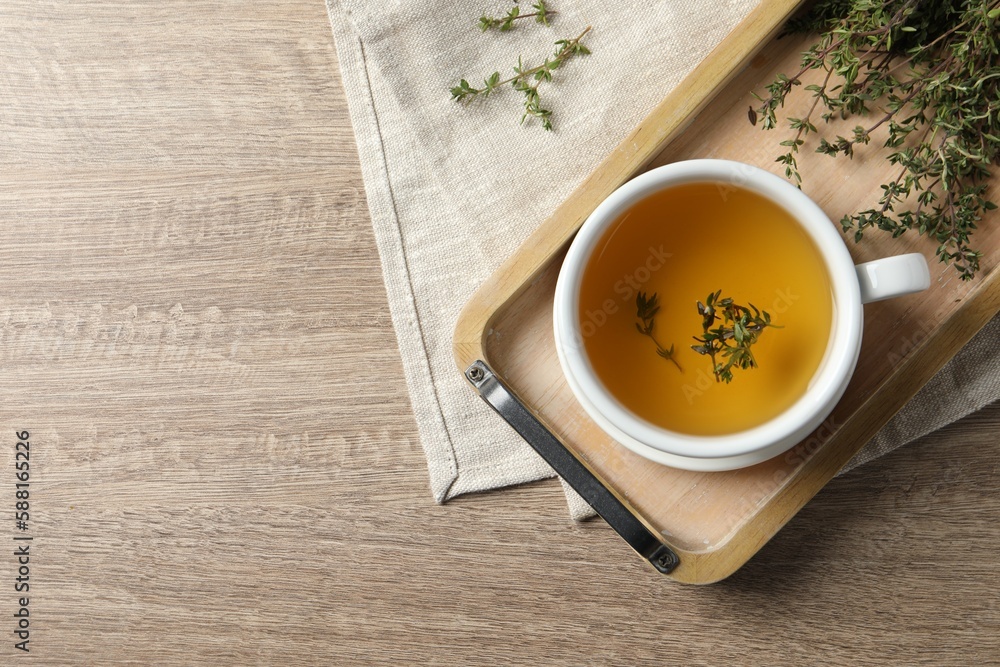 Cup of fresh thyme tea on wooden table, flat lay. Space for text Cup of fresh thyme tea on wooden table, flat lay. Space for text