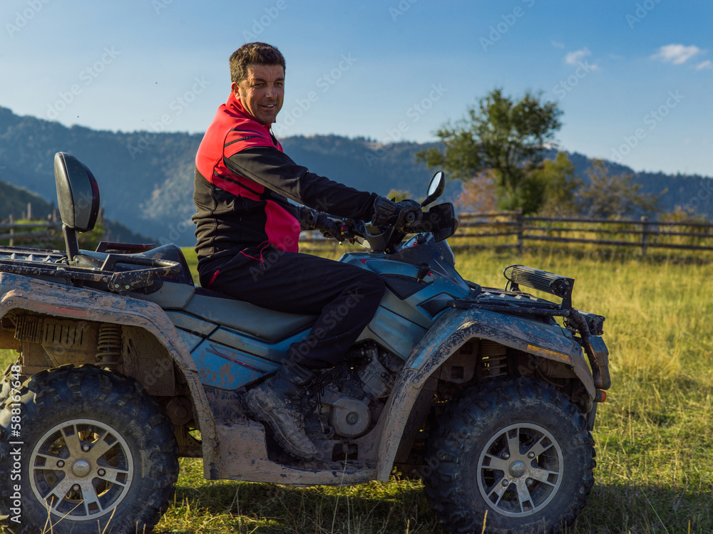 Fototapeta premium A man driving a quad ATV motorcycle through beautiful meadow landscapes