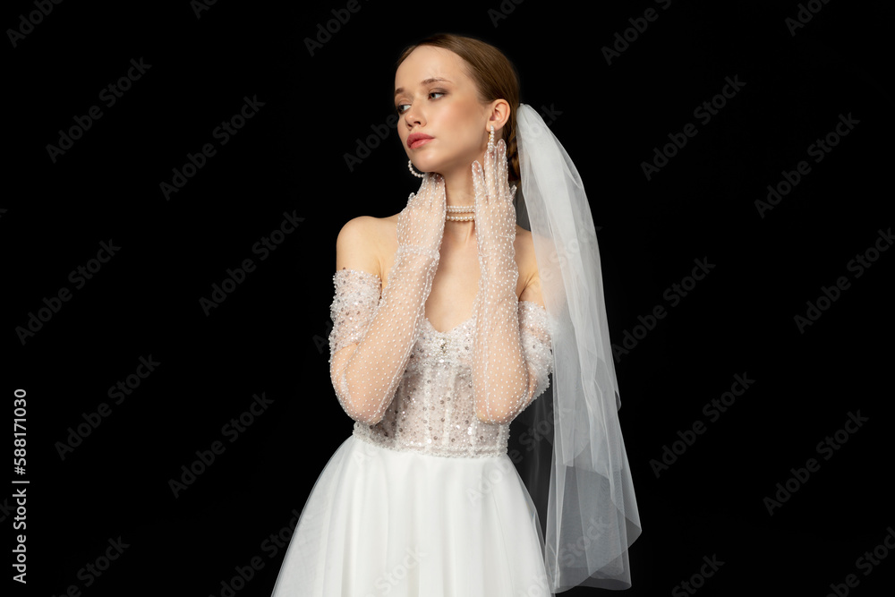 Close-up Portrait of a beautiful charming girl, the bride in a luxurious and elegant white wedding dress, poses and gesturing tenderly. Isolated on a black background.