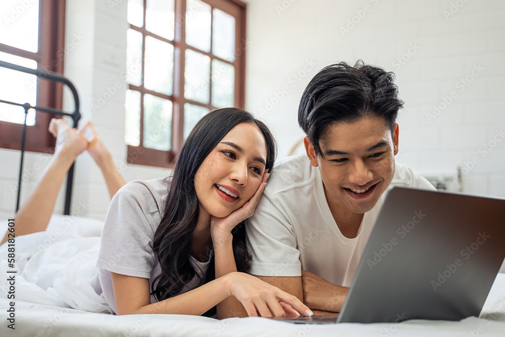 Asian attractive woman using laptop on bed with husband in the morning. Asian attractive woman using laptop on bed with husband in the morning.