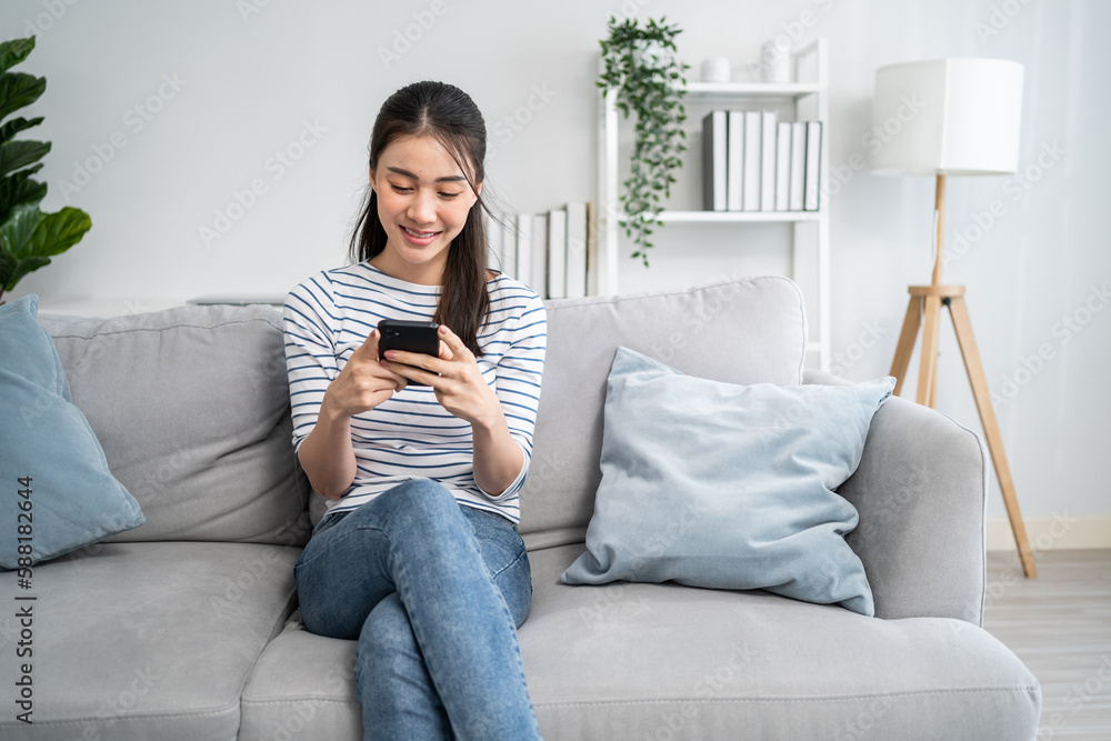 Asian beautiful woman sitting on sofa and swipe mobile phone in house. Asian beautiful woman sitting on sofa and swipe mobile phone in house.