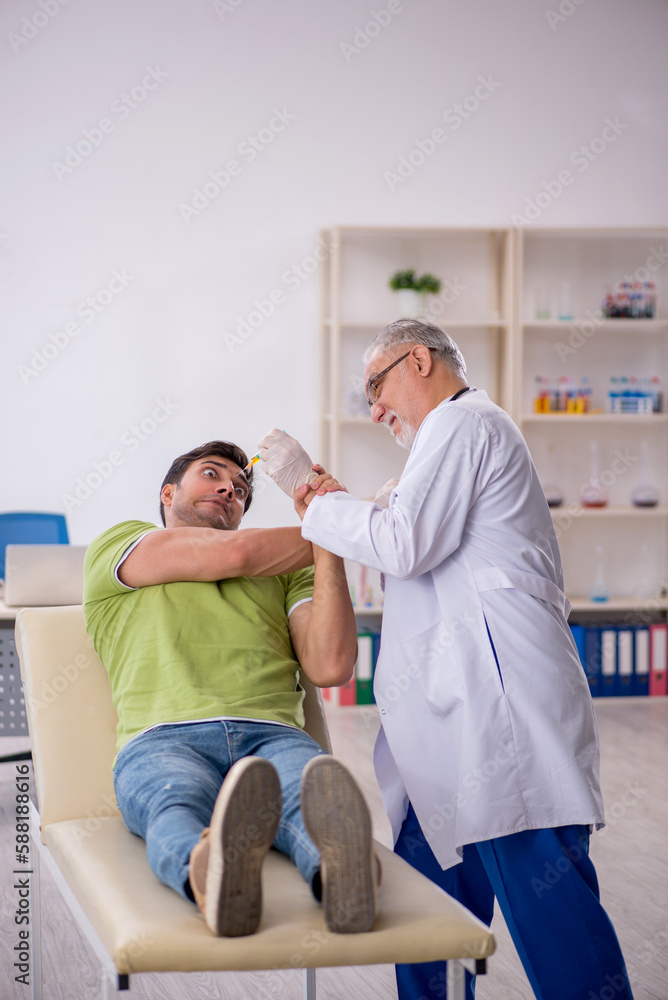 Fototapeta premium Young male patient visiting old male doctor in vaccination conce