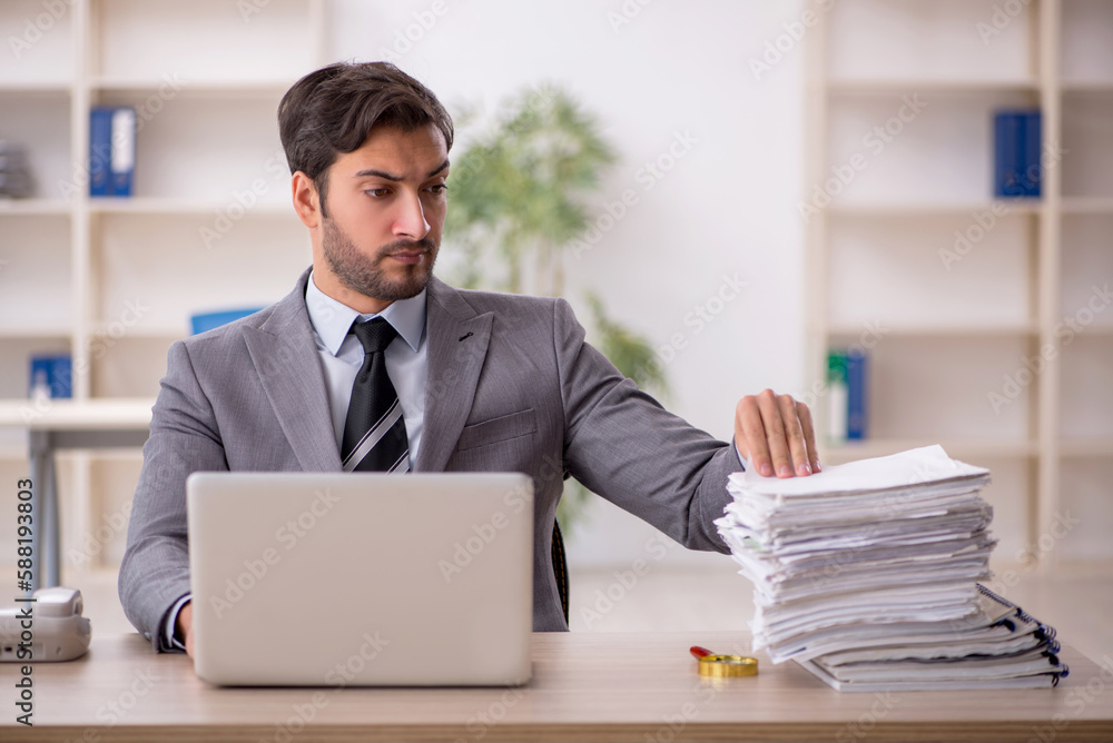 Young male employee and too much work in the office Young male employee and too much work in the office