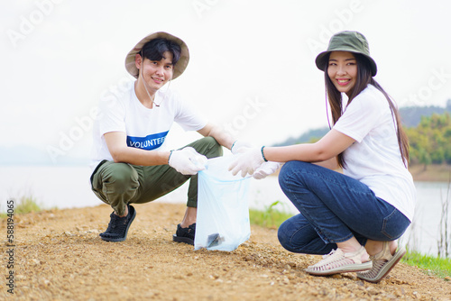 Group of Asian young people volunteer helping to collecting or picking up a plastic bottle garbage on the ground in park. 