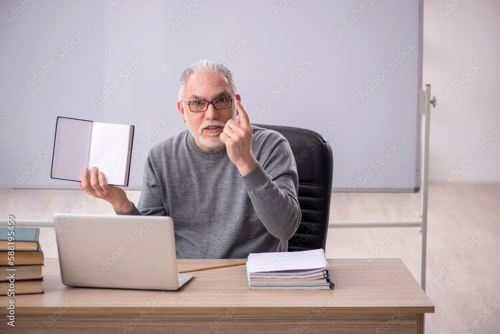 Old male teacher in the classroom Old male teacher in the classroom