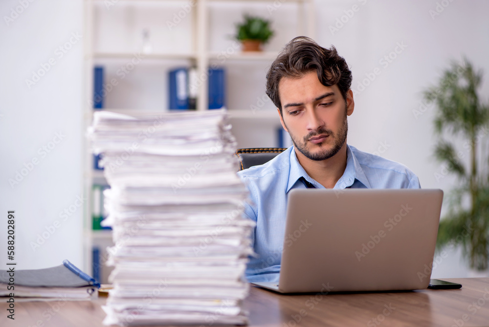 Young male employee and too much work in the office Young male employee and too much work in the office