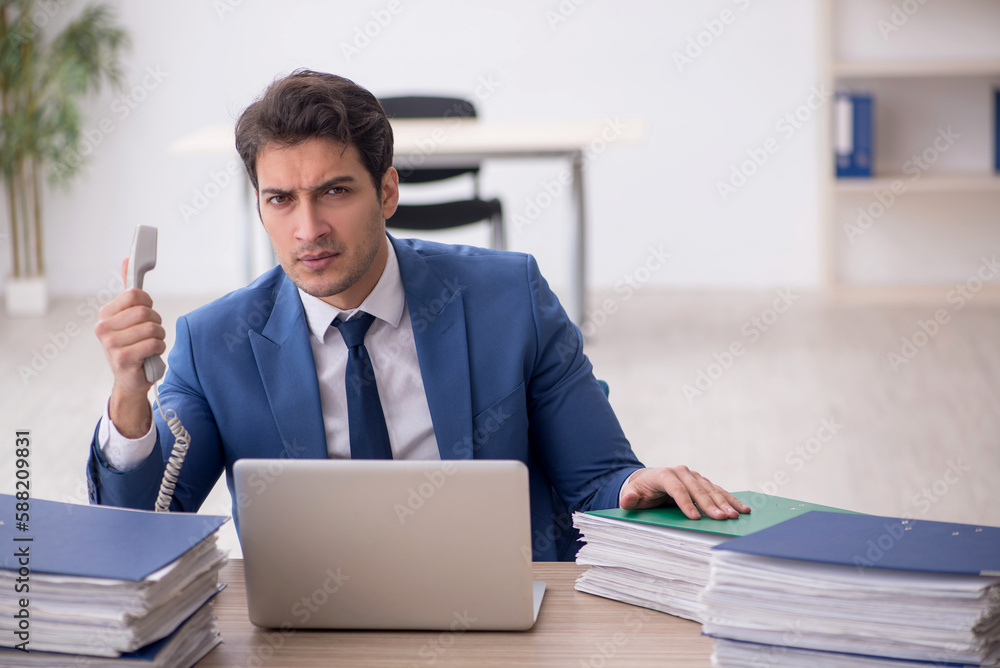 Young male employee and too much work in the office Young male employee and too much work in the office