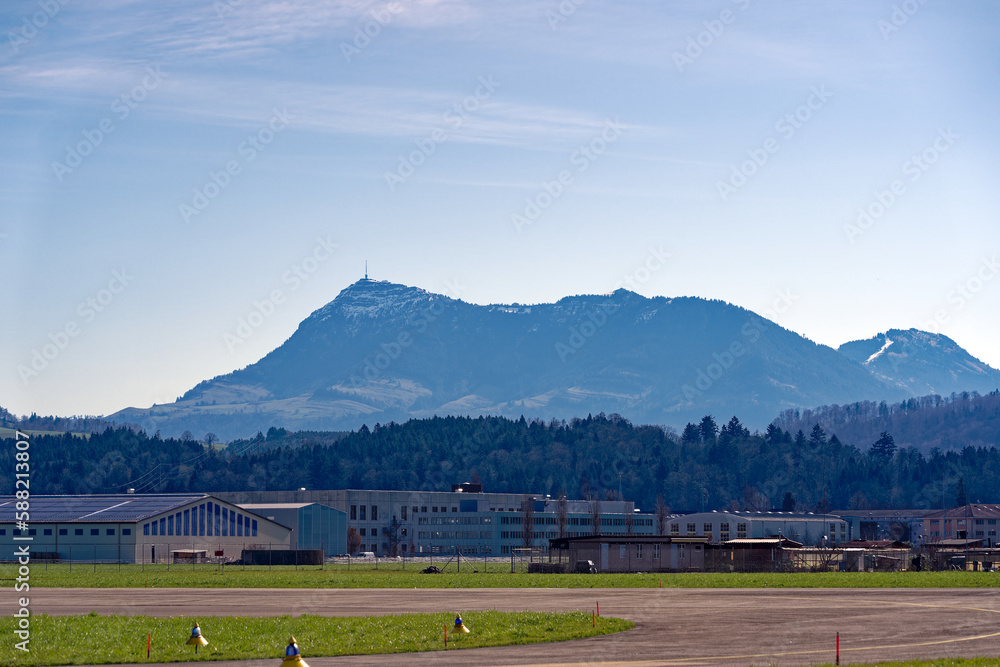 Fototapeta premium City of Emmen, Canton Luzern, with scenic landscape and Swiss Alps with mount Rigi in the background on a sunny spring day. Photo taken March 22nd, 2023, Emmen, Switzerland.