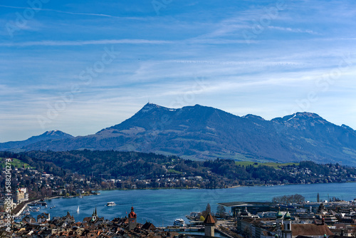 Aerial view of famous Swiss City of Luzern with Reuss River, Chapel Bridge, Lake Lucerne and Swiss Alps on a sunny spring day. Photo taken March 22nd, 2023, Lucerne, Switzerland.