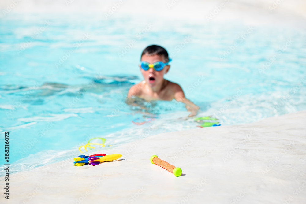 A Caucasian elementary school boy plays in the pool.