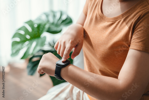 young woman looking and using a smartwatch  Female sitting on the sofa checking her smartwatch.