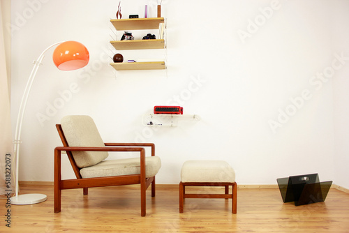 Armchair with Ottoman Danish Design in a Cosy Modern Furnished Living Room 60s Style Interior with a Wall Shelf and a Typewriter in the Background Orange Lamp wooden floor