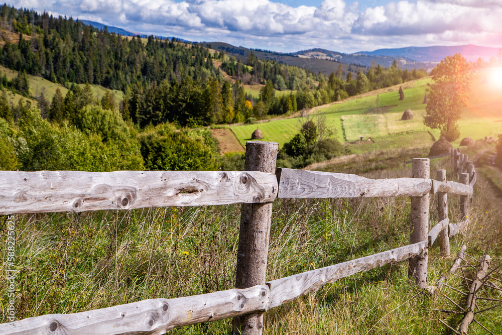 wooden fence near fields on hills with forest. countryside