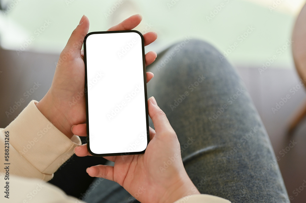 A female relaxing on a sofa and using her smartphone, close-up image