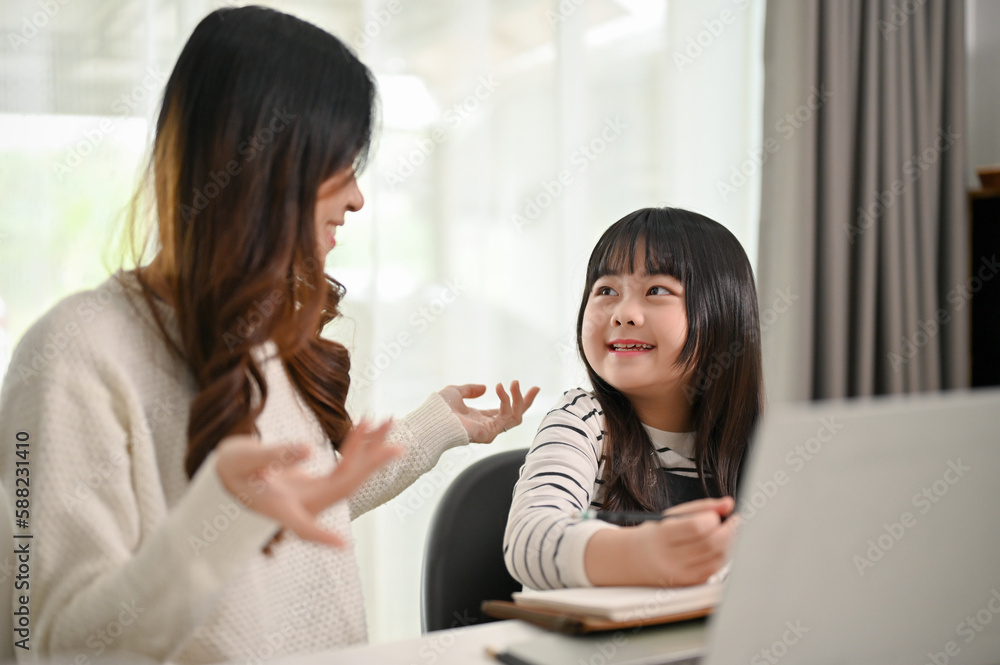 An adorable young Asian girl talking with her mother while doing fun activity at home together. An adorable young Asian girl talking with her mother while doing fun activity at home together.