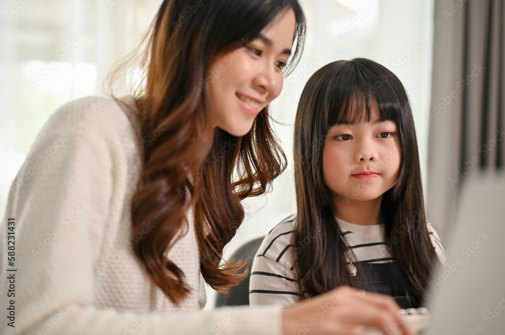 Kind Asian sister helping her little sister with online learning on laptop at home. Kind Asian sister helping her little sister with online learning on laptop at home.