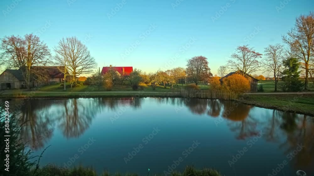 Lake with houses and trees in the background. time-lapse of the sun moving in the sky day to night on the pond. beautiful reflection on the water
