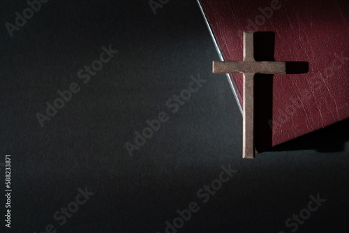 Wooden crucifix cross on a leather cover bible. Top view, copy space.