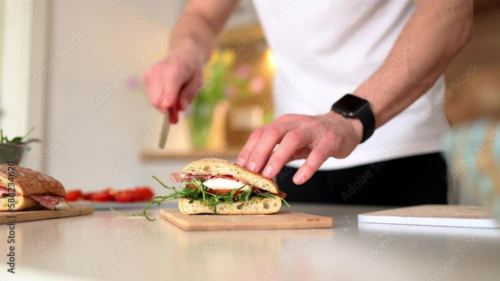 Handsome young man slice Italian sandwich and show what inside. Delicious lunch at home Handsome young man slice Italian sandwich and show what inside. Delicious lunch at home