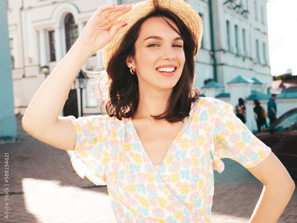 Beautiful smiling brunette model. Trendy female posing in the street background. Funny and positive woman having fun outdoors at sunset. In hat at sunny day. In dress
