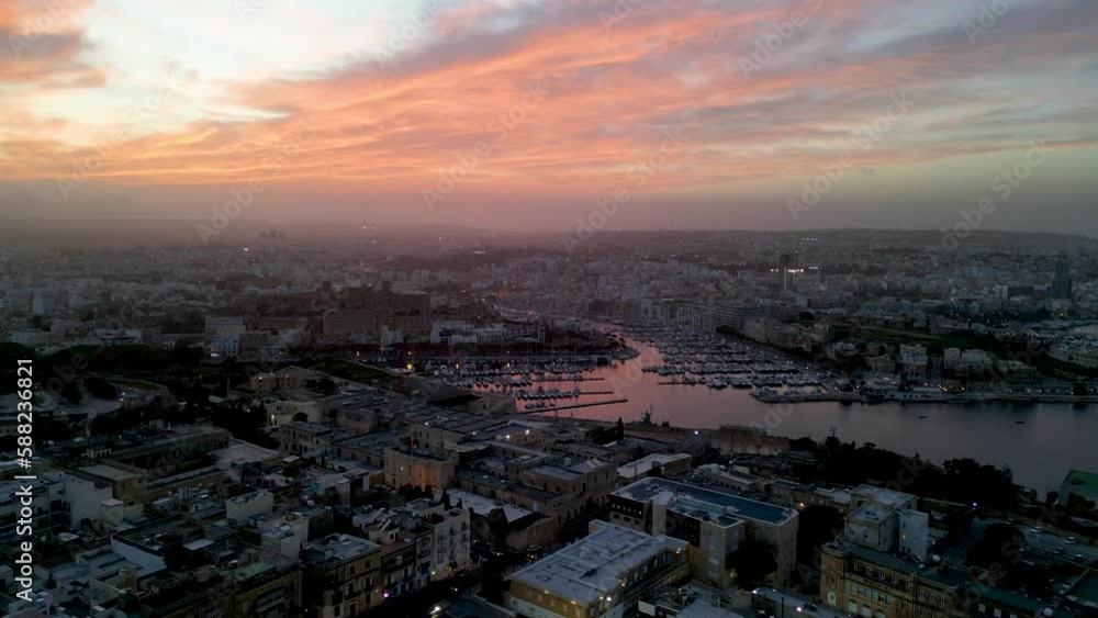 Sunset in Valletta the Capital city of Malta with boat marinas and fiery clouds, Aerial flyover view Sunset in Valletta the Capital city of Malta with boat marinas and fiery clouds, Aerial flyover view