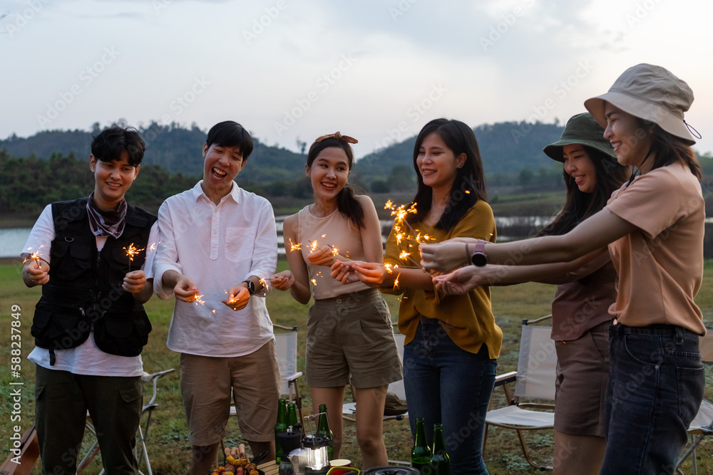 Happy friends holding fire sparkles. Group of young Travel join in fun at camping party in nature. Vacationers enjoy camping at picnic. friendship vacation relax concept. Happy friends holding fire sparkles. Group of young Travel join in fun at camping party in nature. Vacationers enjoy camping at picnic. friendship vacation relax concept.