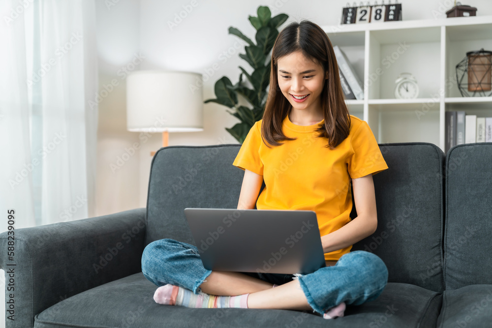 Young cheerful woman sitting on sofa and using laptop computer at home. Young cheerful woman sitting on sofa and using laptop computer at home.