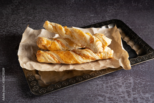 Delicious cheese sticks made of puff pastry with spices on a silver tray
