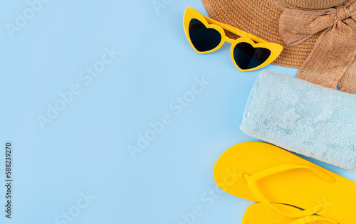 Top view with copy space of sandals with hat and sunglasses on blue background.