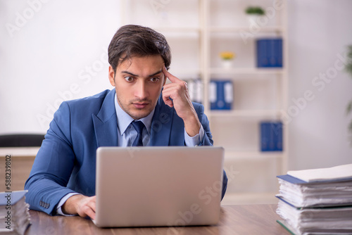 Young male employee and too much work in the office