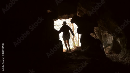 Young Tourist Woman Comes Out of the Cave Into the Light and Rejoices with Her Arms Outstretched, High Quality 4K Travel Andventure Concept Cinematic Footage, Thailand. photo