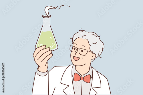 Laboratory assistant holds flask with green fuming liquid while examining chemical reaction