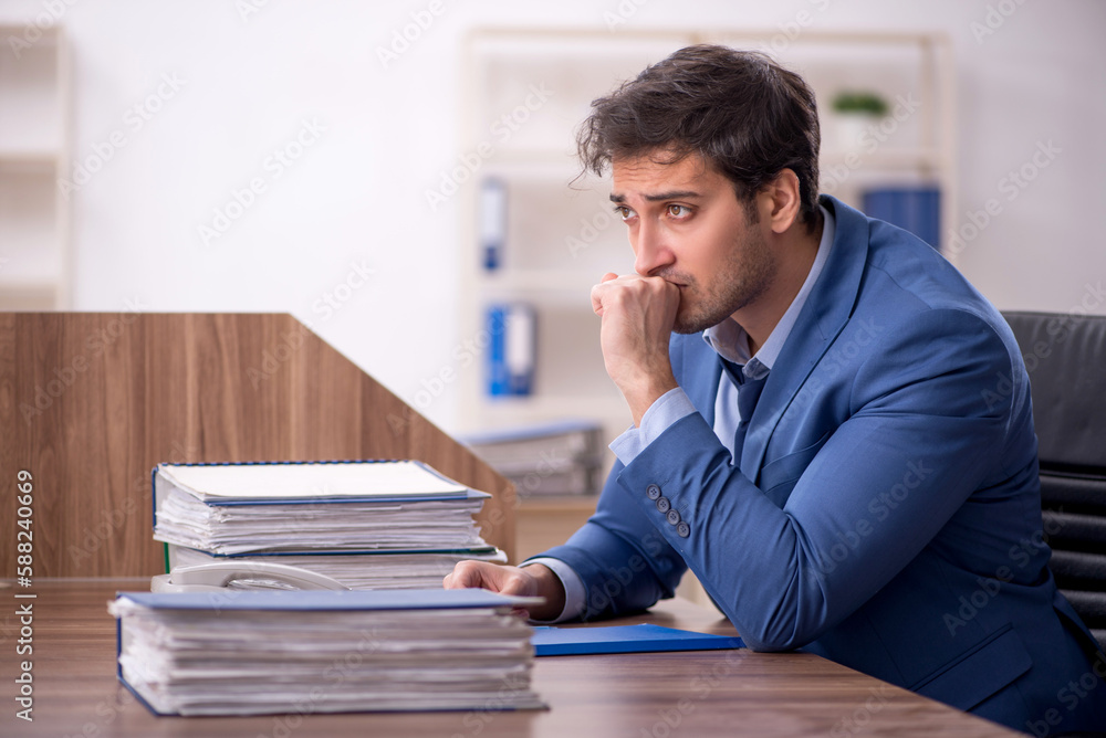 Young male employee and too much work in the office Young male employee and too much work in the office
