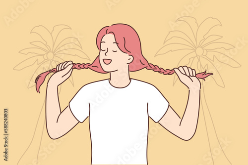 Young woman holding pigtails standing on beach with palm trees for metaphor for inner child